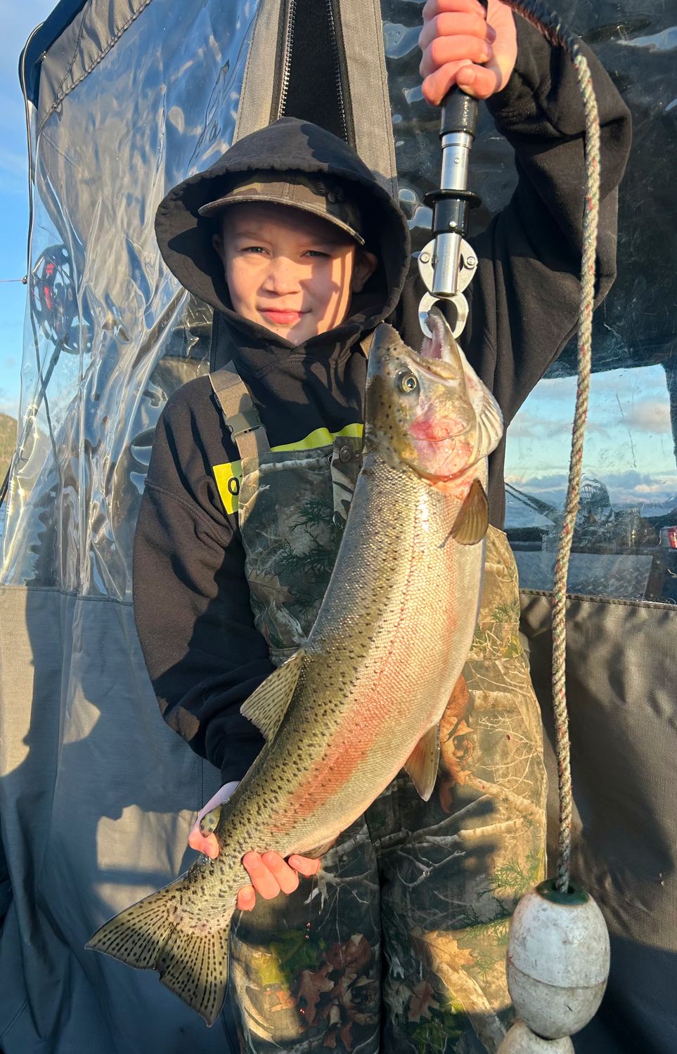 A young angler holding up a big Okanagan Lake rainbow trout caught on a half day charter